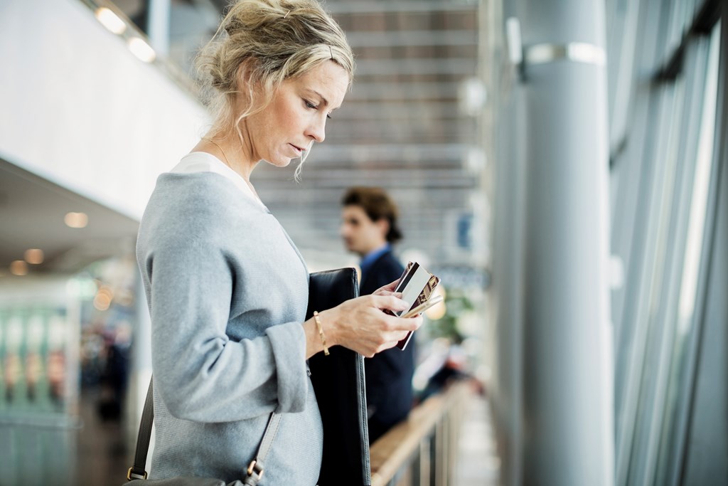 En kvinne på flyplassen med en mobiltelefon i hånden