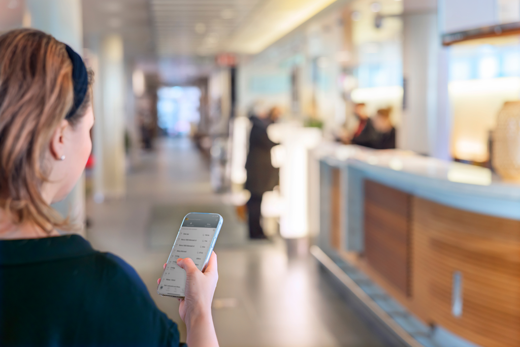 Woman in hotel lobby holding up smartphone