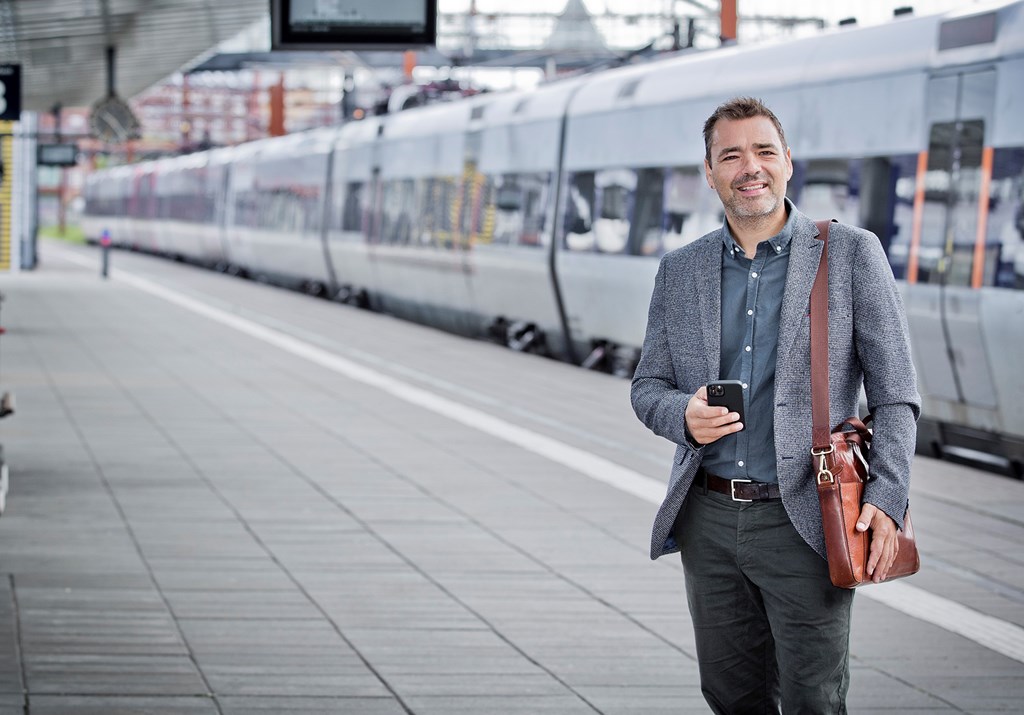 Man in relaxed suit in front of train