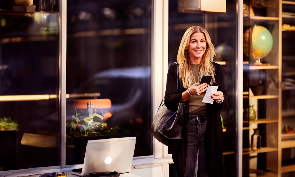 Zofie Sandman from Eatery carries a large black bag over her shoulder, while she reports receipts on her mobile phone.