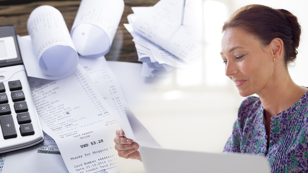 Woman flips through papers and receipts, in front of her is a calculator.